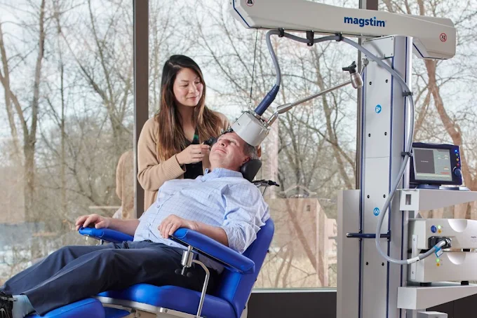 A clinician positioning the TMS coil for a patient during treatment